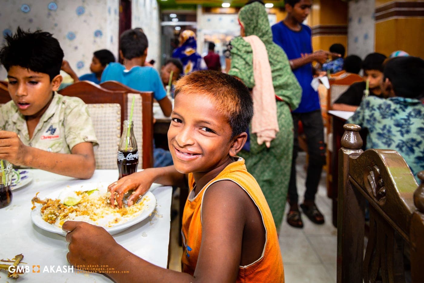 A smiling boy eating a plate of biryani.